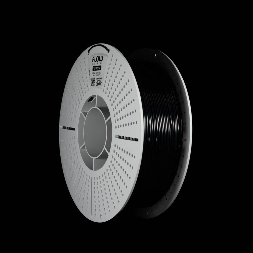 A spool of black 3D printer filament in black colour on a solid black background. The spool has a white outer rim with a circular vented pattern, with the brand name 'FLOW' printed on the spool.