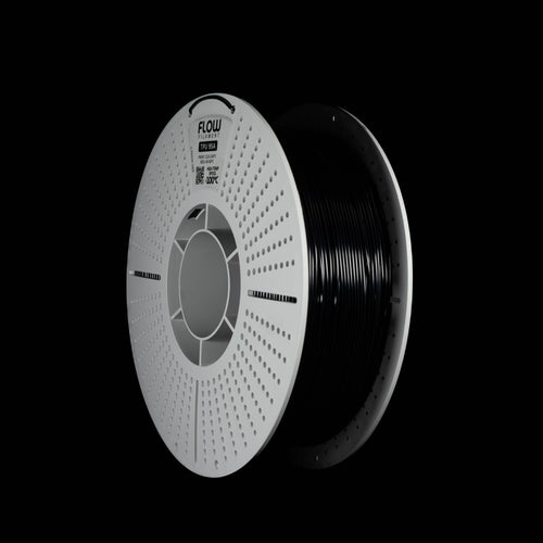 A spool of black 3D printer filament in black colour on a solid black background. The spool has a white outer rim with a circular vented pattern, with the brand name 'FLOW' printed on the spool.