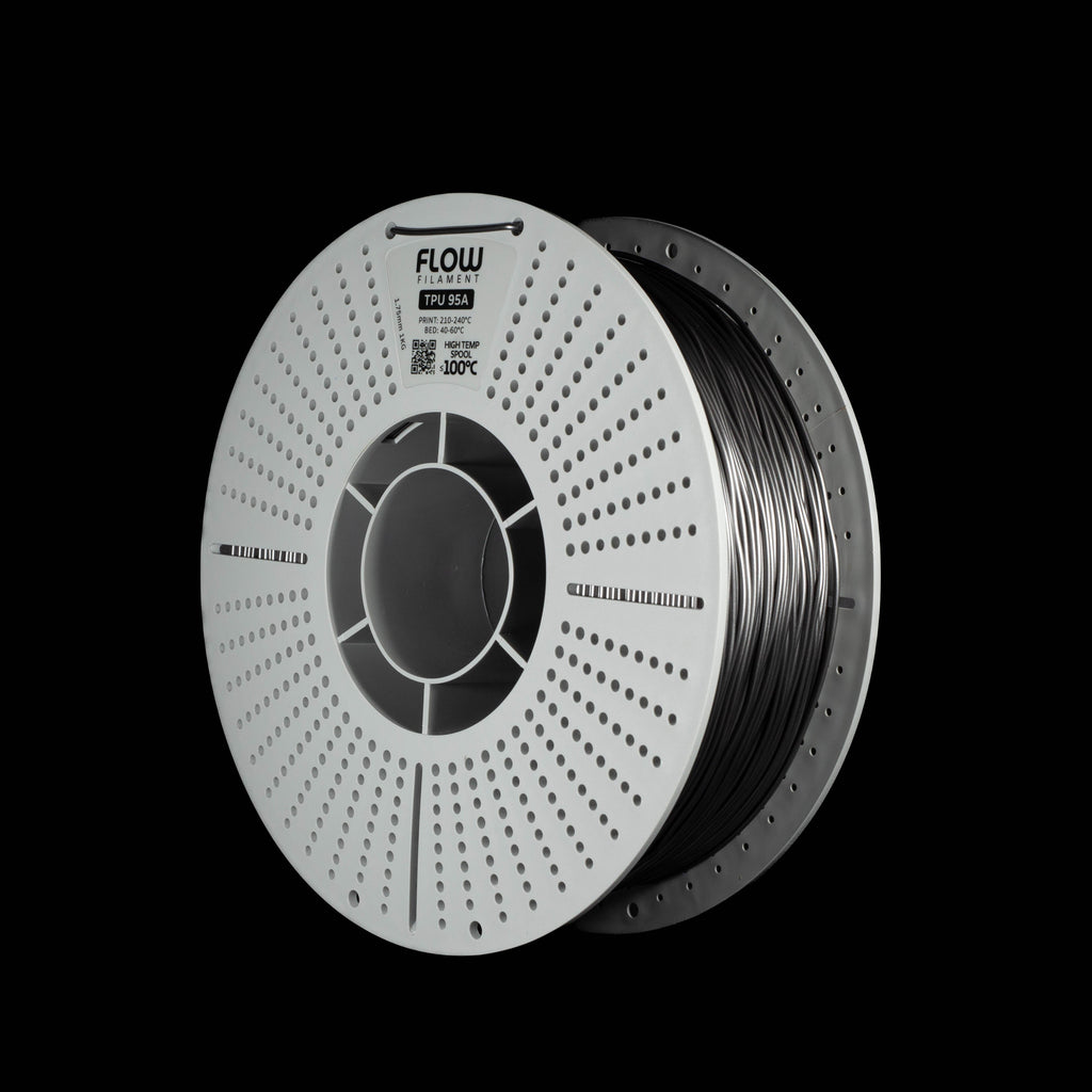 A spool of metallic space grey 3D printer filament on a solid black background. The spool is white with a circular perforated design and features the brand name 'FLOW' printed on the top.