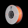A spool of orange 3D printing filament on a white spool, shown against a solid black background. The brand name 'FLOW' is visible on the top of the spool.