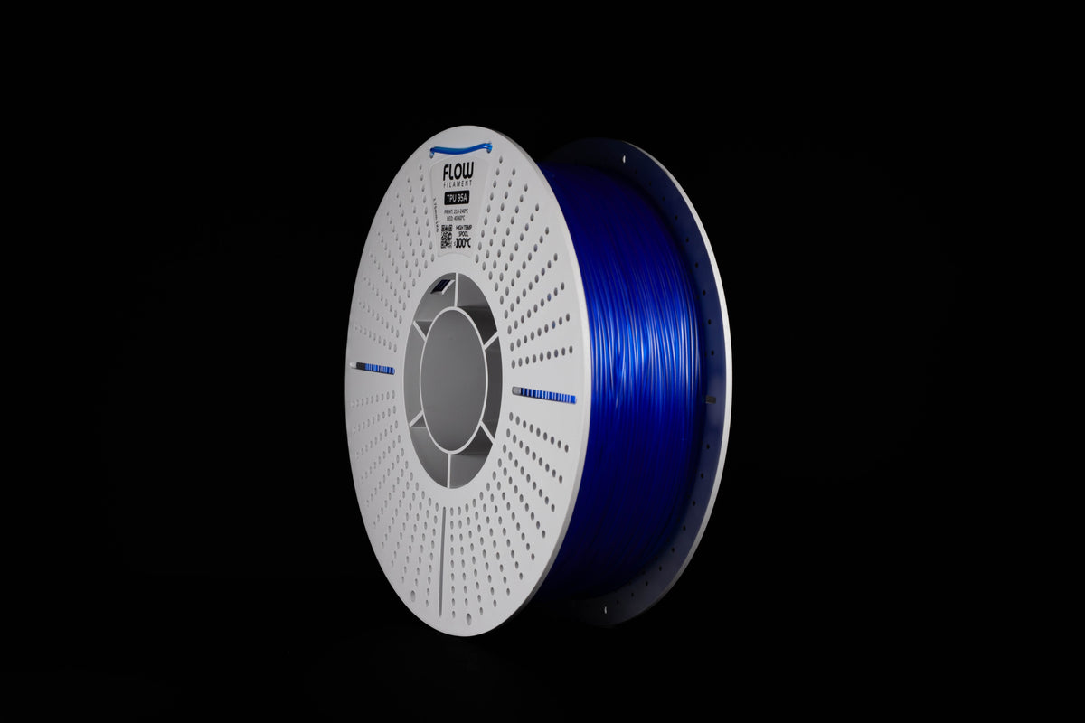 A spool of translucent blue 3D printer filament on a black background, featuring a white perforated spool with the brand named FLOW.