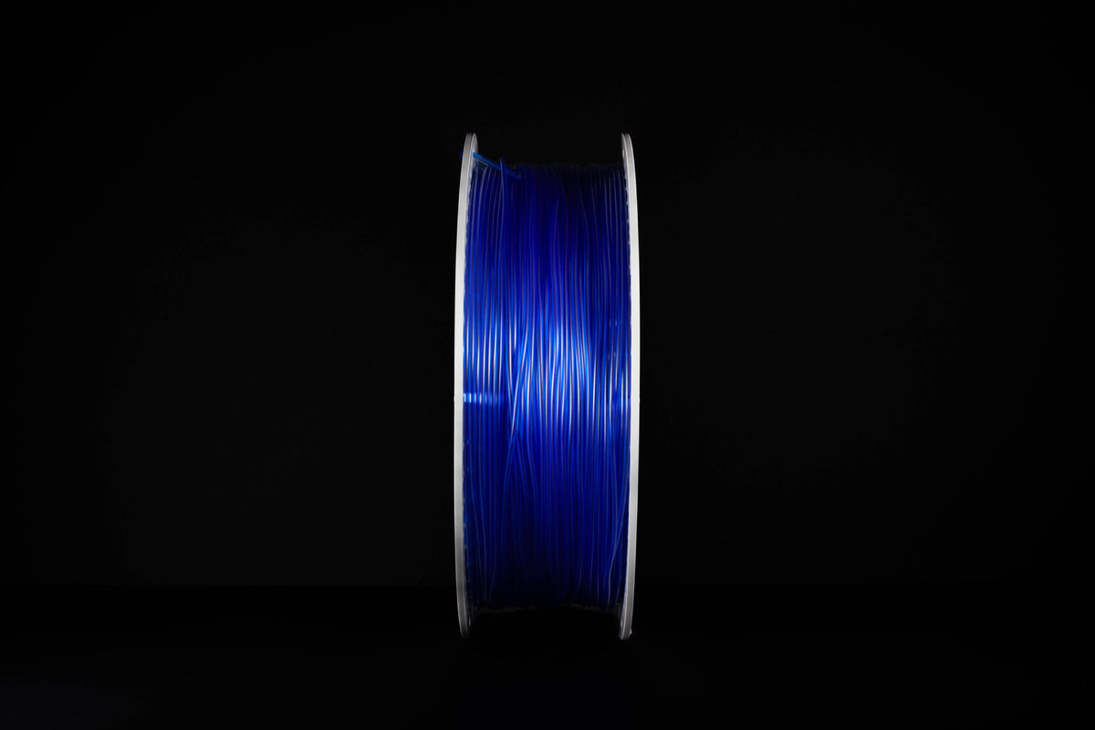 A spool of translucent vibrant blue 3D printing filament standing vertically against a solid black background.