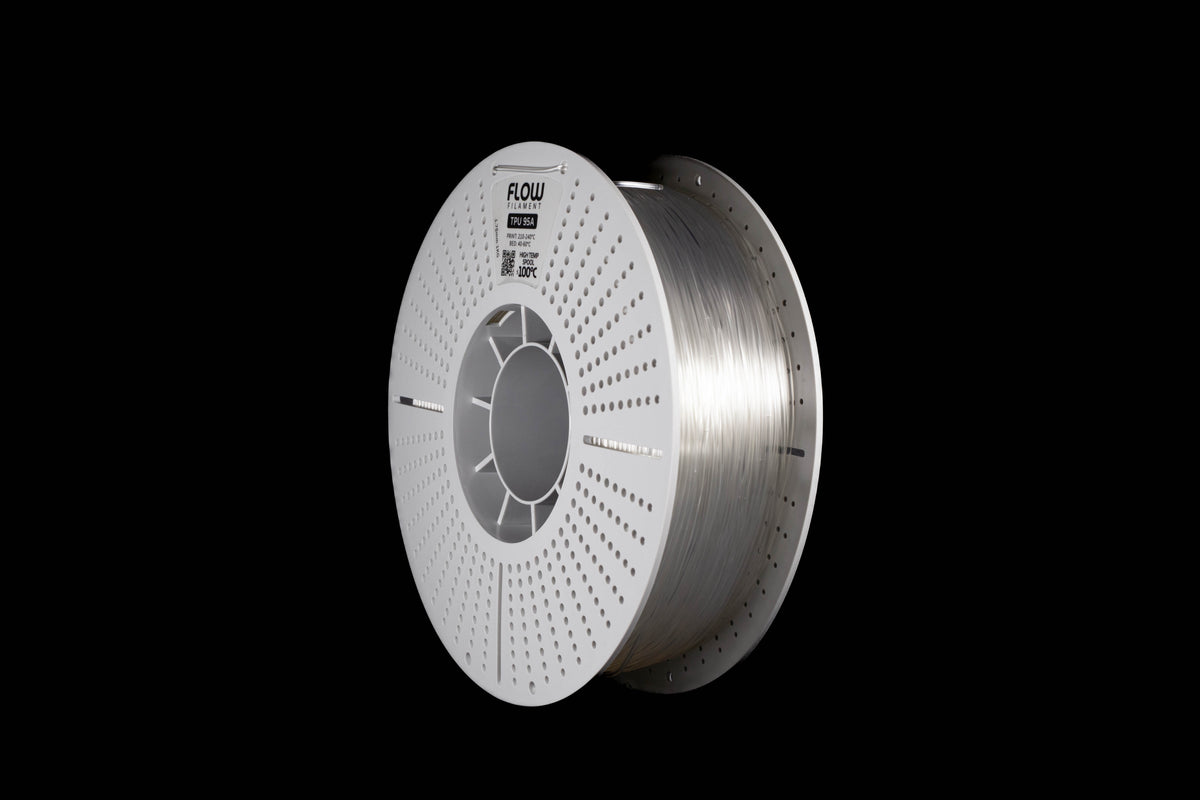 A spool of transparent-colored 3D printing filament on a solid black background. The spool is white with a circular perforated design, and the brand name 'FLOW' is printed on the top.