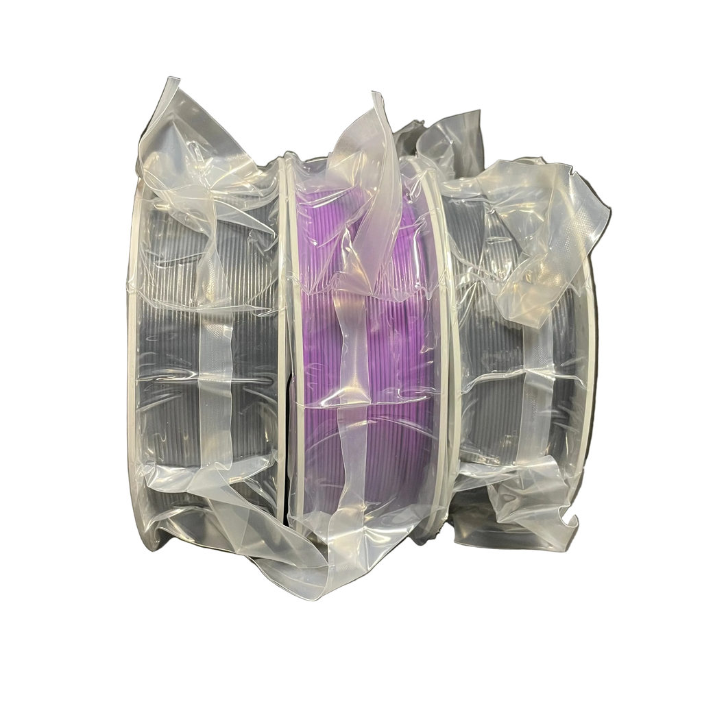 Three spools of 3D printing filament wrapped in clear plastic, with the center spool showing purple filament.
